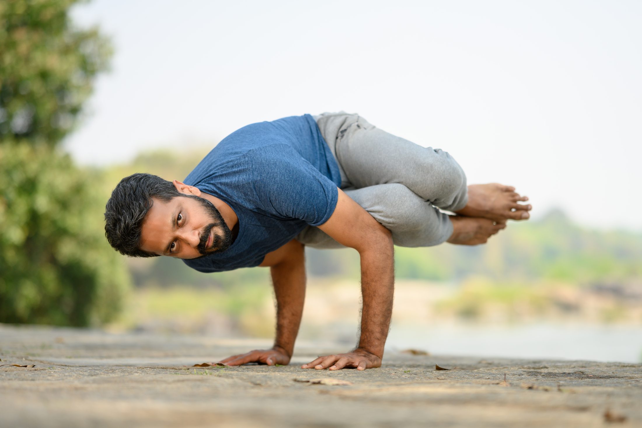 Ankur Bhati holding an arm balance beside the river