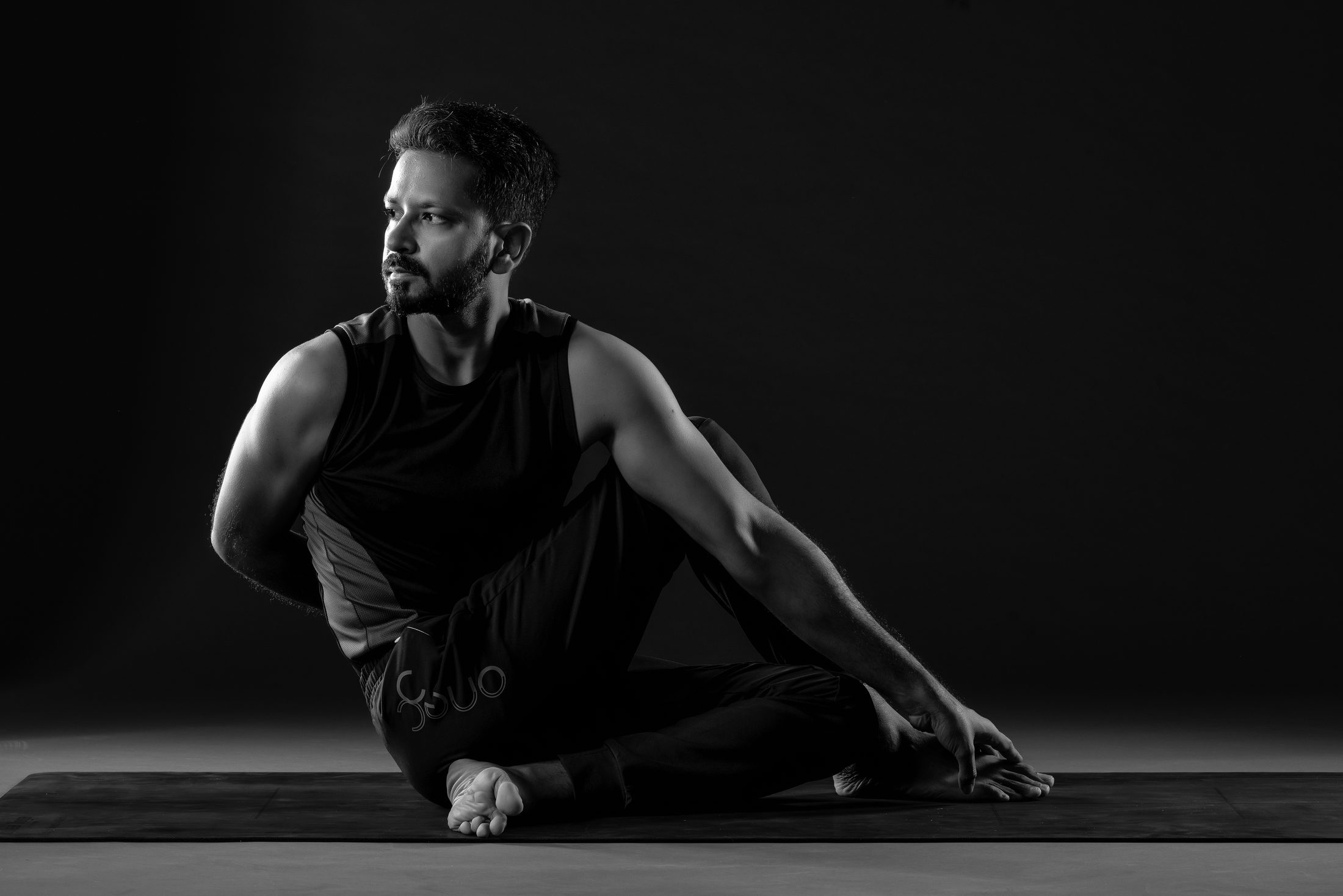 Ankur Bhati in a seated twist against a dark background