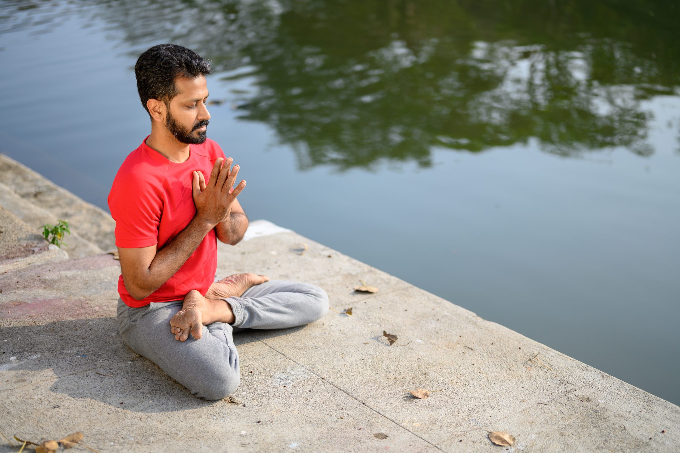 Ankur Bhati seated in prayer beside still water